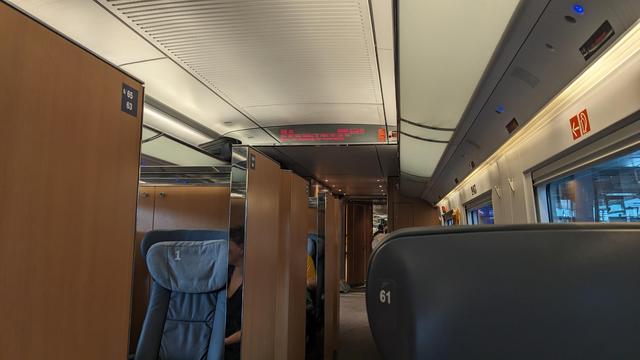 Interior of a comfortable first class salon with semi-compartments, single seats and a timeless wood and blank metal design.