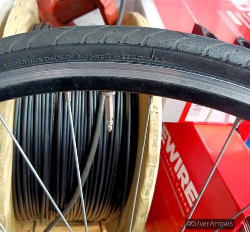 A close up showing the recommended tyre pressure info over the valve on a bike tyre