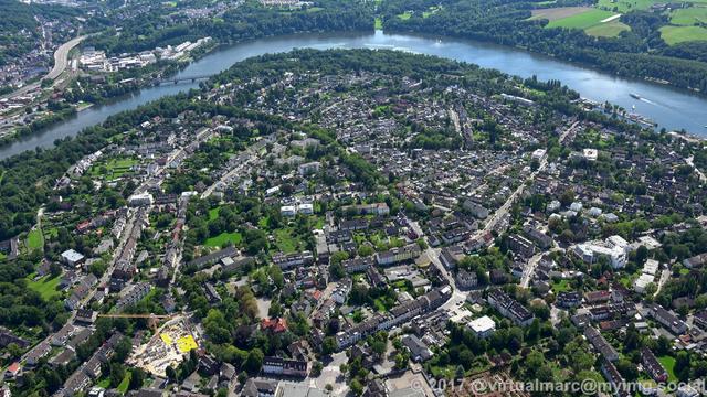 An aerial photo of Essen Heisingen. You can see multiple living quaters sourrounded by trees. The ruhr river can be seen as an upside down shaped U at the top.