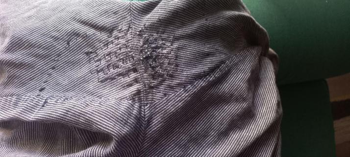 la entrepierna de unos pantalones de finas rayas blancas y negras, muy remendada.