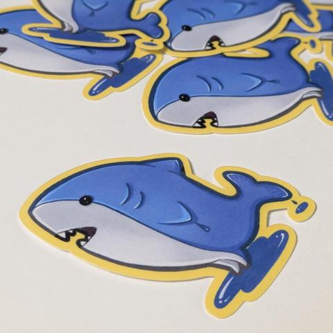 Stickers of the ffxiv minion major general, a little shark with legs. He's standing in a puddle of water, and water is dripping off its tail.