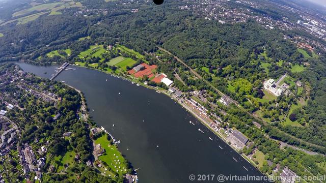 An aerial photo of the Baldeneysee. You can see Villa Hügel in the right, sourrounded by many trees. There are small sailing boats on the lake. The Dam weir of the Baldeneysee can be seen at the left.