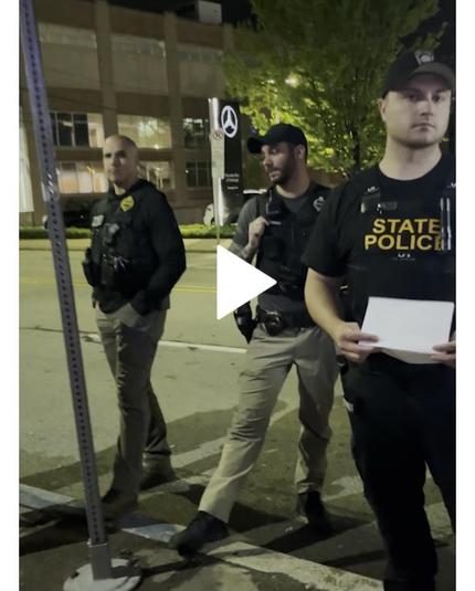 Screenshot of a video embedded in the article. It shows three white cops. A bald one, and then two wearing baseball style caps, the middle guy is not looking at the camera but the other two are.
The dude closest to the camera is wearing a shirt that says state police. 

I want people to see their faces, I want these men to be shamed and shunned
