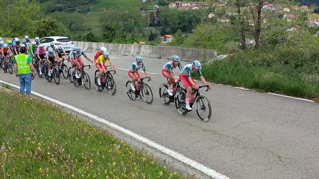 The leading bicycle team in red, white and green team colors pulling the bunch up the hill after the break away group further ahead.