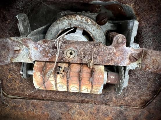 Closeup of the odometer, where a speedometer cable snaking its way up from transmission area to hook to gears that rotate a dial to indicate speed using a dial coming out of the empty hole in the middle and below that it would drive other gears to slowly tick over a series of numbered wheels to track total miles. This may be showing 12193x for mileage, or depending on angle it could be 23204x (‘x’ means I can’t read that dial).