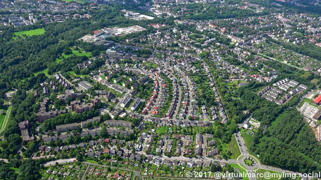 An aerial photo of the northern side of essen with many living quaters in a green environment sourrounded by trees.