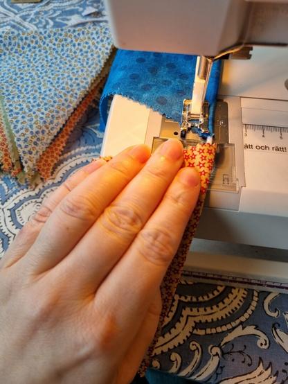 A closeup on a hand sewing on a sewing amchine.
