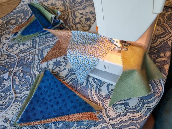 A picture of the sewingmachine from the side, showing how you sew all the pennants on the string in one long seam.