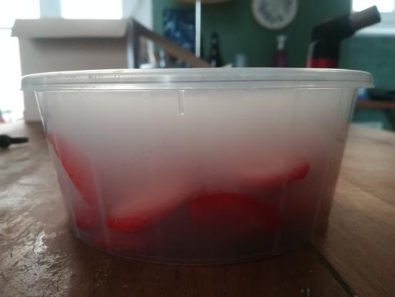 Fraises coupées en tranches dans une boîte plastique remplie de fumée.