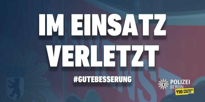 Alt-Text: Das Bild zeigt ein Motiv der Polizei Berlin. Im oberen Bereich steht in großen, weißen Großbuchstaben über zwei Zeilen "IM EINSATZ" und darunter "VERLETZT", jeweils mit einem leichten Schattenwurf. Unterhalb des zentralen Schriftzugs ist in weißer Schrift der Hashtag "#GUTEBESSERUNG" platziert. Links im Bild ist schemenhaft und in blauen Farbtönen ein Teil des Berliner Wappens oder ein daran angelehntes Symbol mit dem Berliner Bären in einem Schild und einer Krone zu sehen, umrahmt von einem sternförmigen Element. Im rechten unteren Bildbereich befindet sich das offizielle Logo der Polizei Berlin, bestehend aus einem Sternsymbol mit dem Bären und daneben dem Text "POLIZEI BERLIN". Direkt darunter ist ein gelbes Rechteck mit der Aufschrift "110 PROZENT BERLIN" zu sehen, wobei die "110" prominent hervorgehoben ist. Der Hintergrund des Bildes ist unscharf und zeigt breite, diagonal verlaufende Farbflächen und Verläufe in Blautönen im linken Bereich sowie in Rottönen (wie Weinrot oder Mauve) im rechten Bereich, was dem Gesamtbild eine dynamische und zugleich ernste Wirkung verleiht. Das Bild ist eine Botschaft der Polizei Berlin zur Unterstützung und Genesung für im Dienst verletzte Polizeibeamte oder andere Einsatzkräfte.