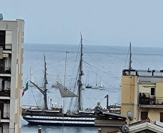 Tra due palazzi fronte mare si vede il veliero Amerigo Vespucci che solca il mare