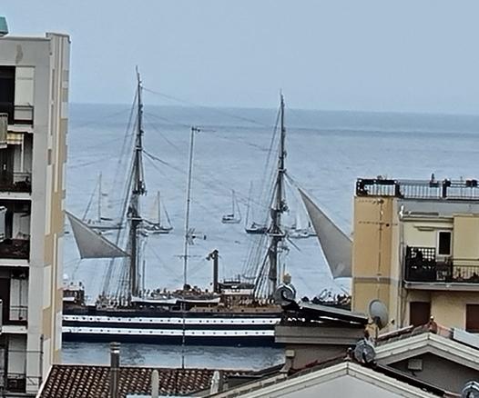 Tra due palazzi fronte mare si vede la nave Amerigo Vespucci che solca il mare