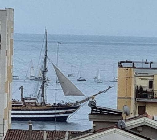 Tra due palazzi fronte mare si vede la nave Amerigo Vespucci che solca il mare