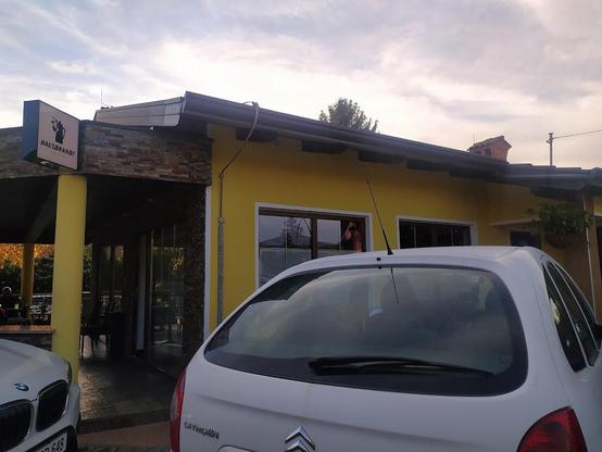A yellow building with a "HAUSBRANDT" sign and two parked cars.
