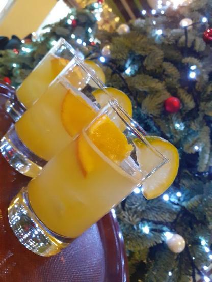 Three cocktails on a tray with a Christmas tree in the background.