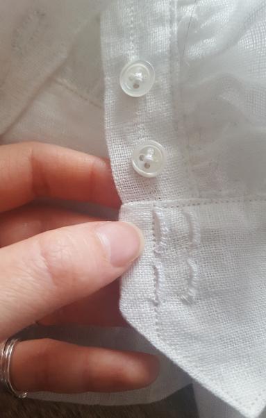 The thread bars on the other side of the waistband, two pairs. They're about 7mm apart, providing a tiny bit of adjustment for room, which doesn't look like much but will have a difference in feel. Two of the small shell buttons are also in frame, very small and lovely and shiny. Being organic they are not quite identical or symmetric, but this is fine, they're quite pretty. Sini's pink fingers are holding onto the edge being shown. The scale is quite small, the individual threads of the fabric weave can be easily made out, the fabric is fine but not incredibly densely woven!
