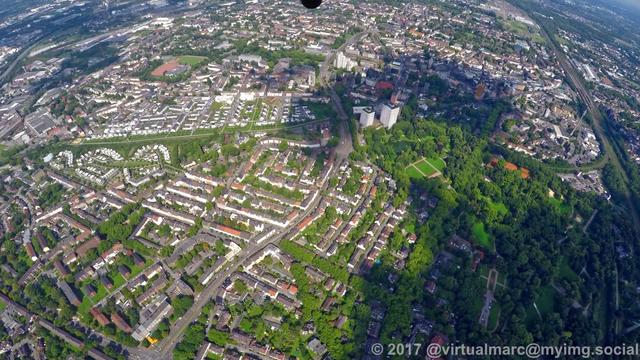An aerial view of Gelsenkirchen center with living quaters inside green oasis with many trees around.