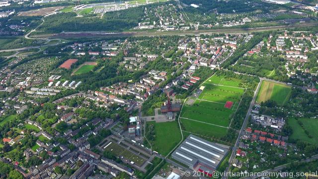 An aerial photo of the consol mine and the consol park. Living quaters sourrounded by trees are nearby. A railway track can be seen at the back.