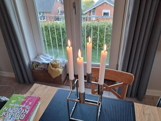 Fire tændte stearinlys foran et vindue, for at markere Danmarks befrielse fjerde maj.