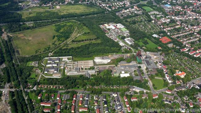 An aerial photo of the pluto mine with the Pluto-Wilhelm spoil heap in the back. All sourrounded by trees.