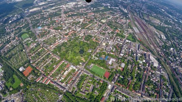 An aerial photo of Wanne-Eickel with the main station at the top right. There are many houses sourrounded by trees. There is a big park in the middle.
