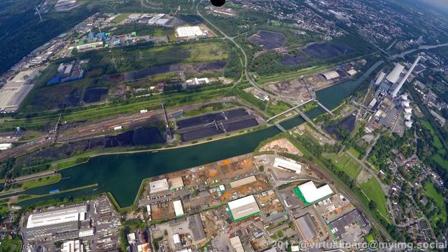 An aerial view of the Rhine-Herne Canal and the Emscher. Between the canal and the river are coal stocks. The Waste-fired power plant of Herten can be seen in the back.