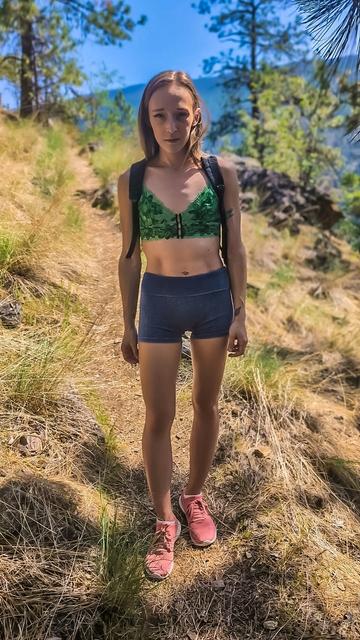 Scarlet is standing there, effortlessly cool, with that playful mix of confidence and charm that’s hard to ignore. The way she rocks that vibrant green top and shorts makes the whole scene pop.
There's something about her that invites a smile. A flirty spark in her eyes making the world around you seem a little brighter. You find yourself wanting to step closer, to keep the conversation going and see that smile light up even more. The perfect combination of adventurous and approachable she makes this hiking trip feel like a spontaneous adventure one that you'd love to share with her.