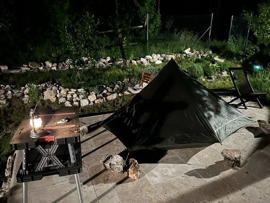 My tent pitched on a paved terrace, at night.