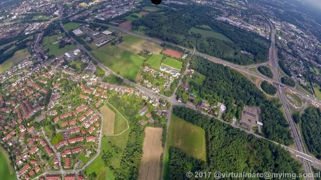 An aerial photo of recklinghausen near the border of herten. You can see a Cloverleaf crossing between two freeways and many trees around. There are also some living quaters sourrounded by trees.