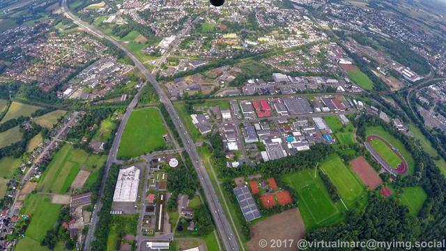 An aerial photo of recklinghausen. There are multiple companies around with green parks and trees. There is a soccer field on the right.