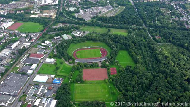 An aerial photo of a soccer field in recklinghausen sourrounded by trees.
