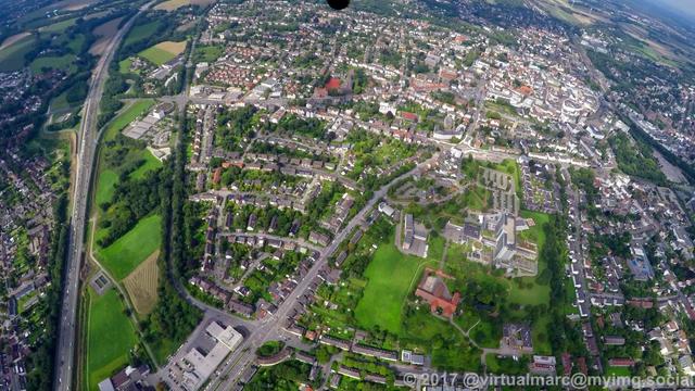 An aerial photo of the center of recklinghausen. There are multiple living quaters and companies sourrounded by trees.