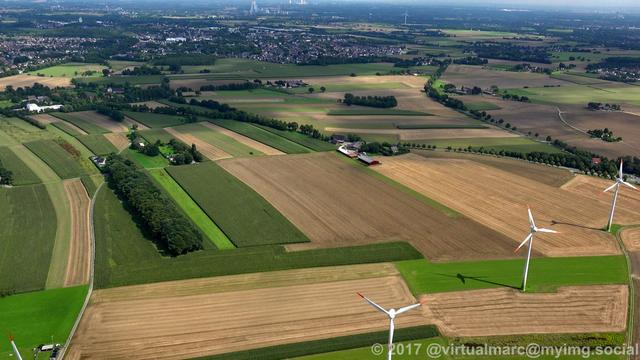 An aerial view of farm yards in Recklinghausen with wind turbines on them.