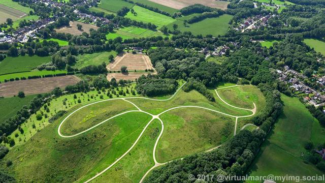 An aerial photo of the spoil heap near the Honermann settlement at the former General Blumenthal 8 mine in Oer-Erkenschwick, sourrounded by trees. There are some houses and a railway track around.