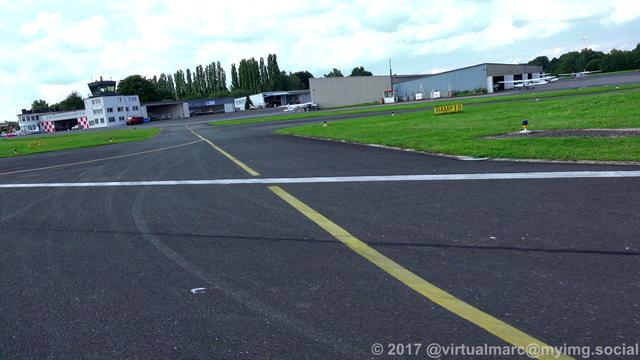 A photo from the runway at the Marl Lohemühle airport while landing the gyrocopter. Some hangers with sport planes can be seen at the top right. The tower can be seen at the top left.