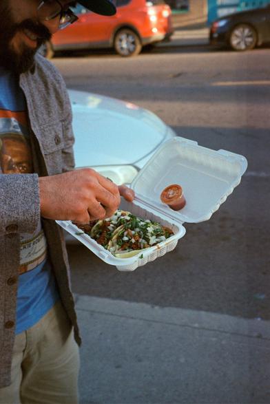 A very happy man squeezing a lime over adobada tacos.