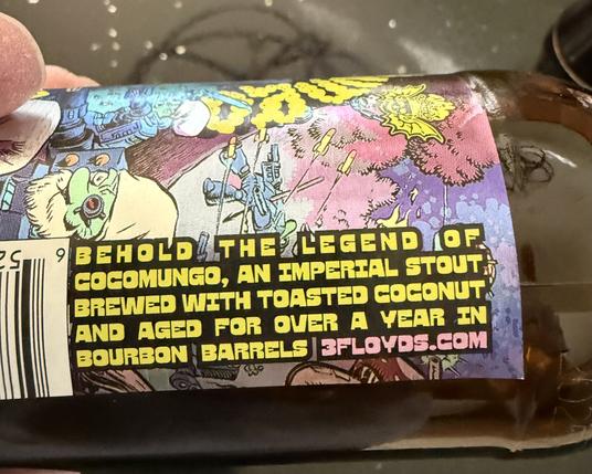 The side label of a bottle of 3Floyds cocomungo stout beer. It says Behold the legend of cocomungo, an Imperial stout brewed with toasted coconut and aged over a year on bourbon barrels
