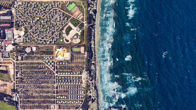 a satellite picture of a seaside resort complex and the sea. th picturee is split in two with the blue sea on the right and the resort + camping on the left