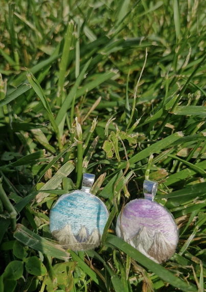 two hand-embroidered pendants lying in grass