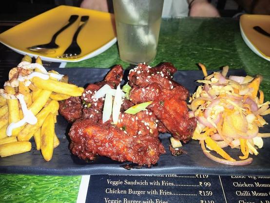 A plate of food with fries, chicken wings, and a salad is on a menu.