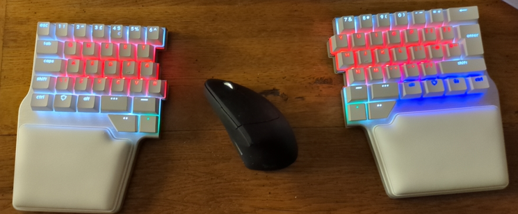 A picture of the ergonomic splitted dygma raise 2 keyboard with m'y mouse between the 2 parts