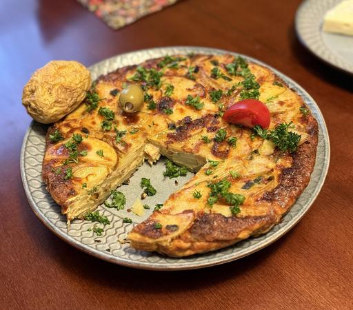 A round Spanish tortilla with a rectangle cut out of one side and a baked potato along the round edge to create a Millennium Falcon shape