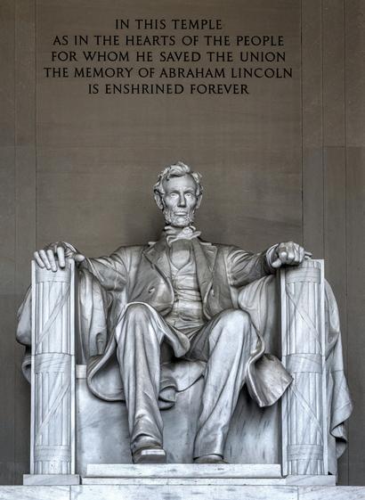 A photo of the statue of Abraham Lincoln in the memorial. Above the statue, the text: IN THIS TEMPLE AS IN THE HEARTS OF THE PEOPLE FOR WHOM HE SAVED THE UNION THE MEMORY OF ABRAHAM LINCOLN IS ENSHRINED FOREVER