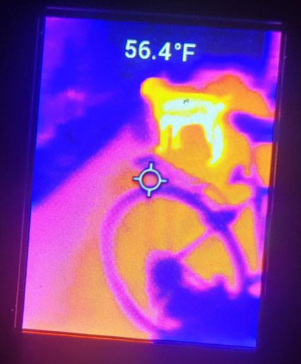 Glowing orange dog shaped object and the ahadow of a bicycle wheel rack and seat seen on a digital display on color, 56.4F readout