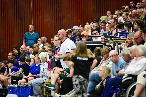 Daniel R. Schmidt steht inmitten der Fans zwischen zwei Tribünen in der Main-Kinzig-Halle. Direkt neben ihm trommeln Fans.