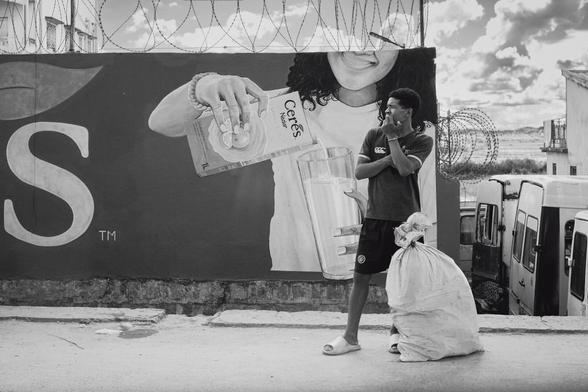 Une personne attendant le taxi-be devant une publicité pour du jus de fruit sud-africain.