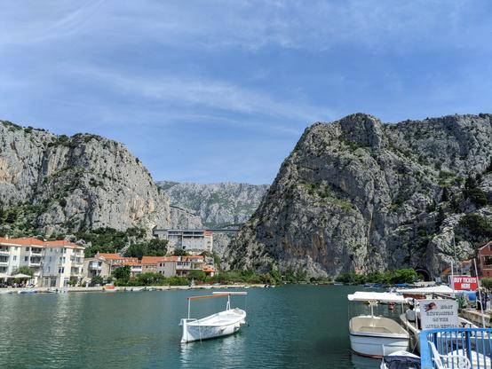 Steep mountain cliff with sailing boats an urban river opening along the Dalmatian coast
