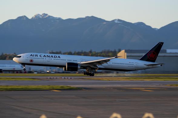 Same position and framing as the previous photo, but this time it is an Air Canada 777-300ER on touch down. The last sets of tires of the main gears have just barely made contact with the ground, so some tire smoke is visible, but the rest of the tires are still in the air.