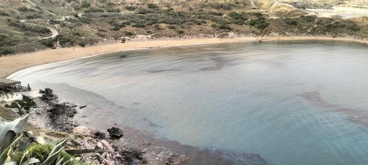Another image looking down into Riviera Bay, the blue green sea laps against the horse shoe shaped bay, gently kissing the orange dusty sand. Trails snake off throughout the rocks and scrub and up along the hills that surround the bay.