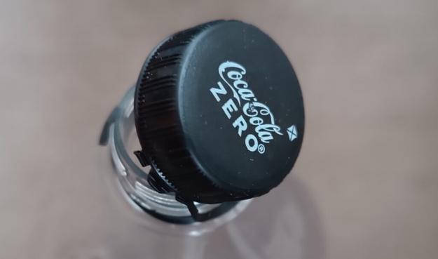 Tapón de Coca-Cola enganchado a la botella de plástico